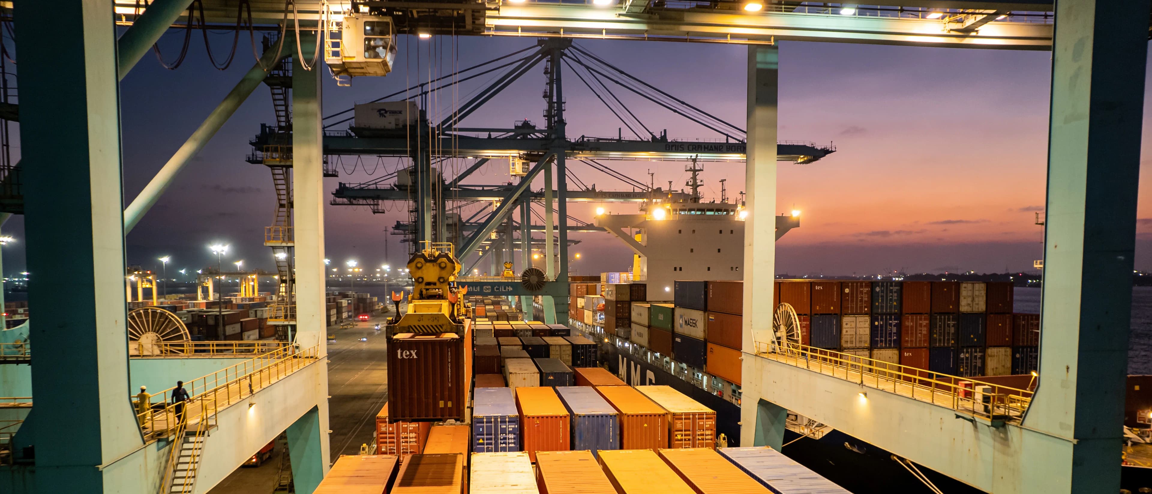 Gantry cranes loading containers at a port at dusk