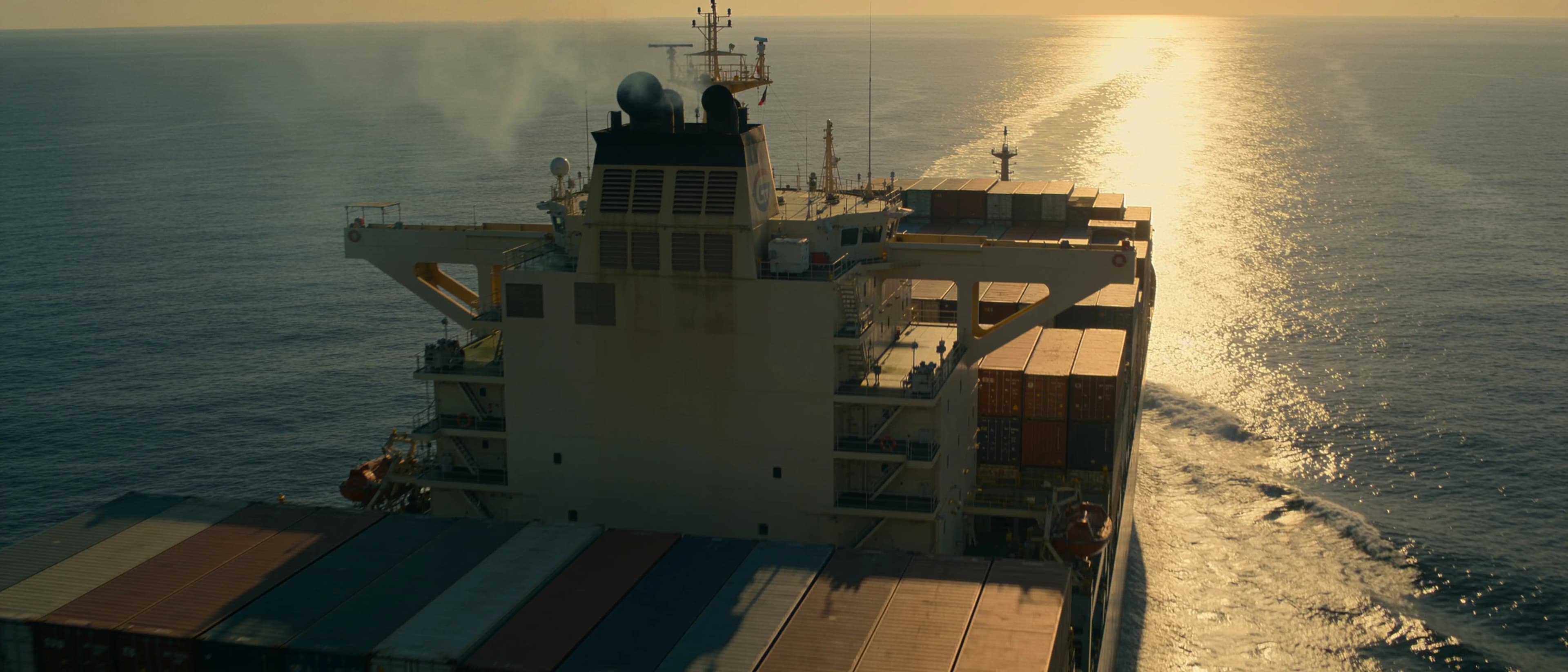 A container ship crossing open sea at sunrise